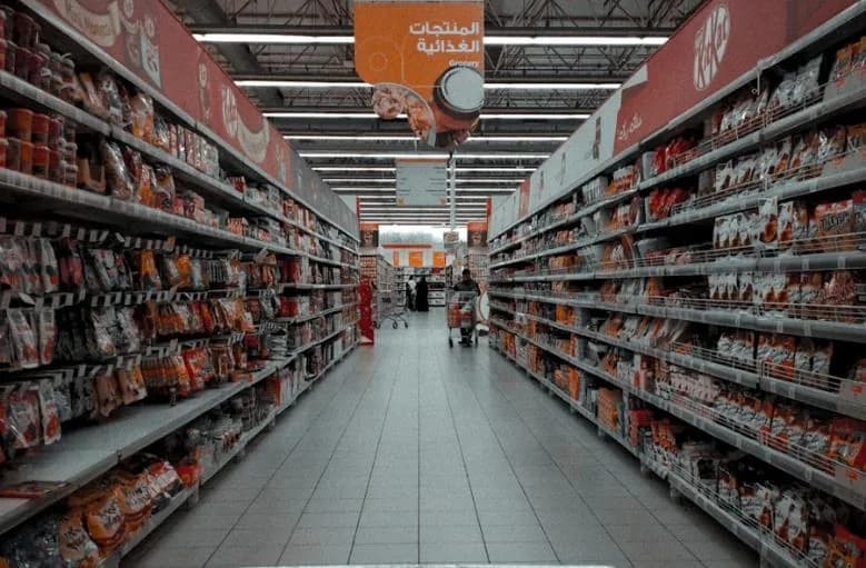 A supermarket grocery aisle with bilingual Arabic and English signage